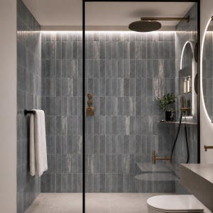Könnte beinhalten: Modernes Badezimmer mit begehbarer Dusche. Die Dusche ist mit grauen, vertikalen Fliesen gefliest. Sie verfügt über einen Regenduschkopf, einen Handtuchhalter mit einem weißen Handtuch und ein kleines Regal mit einer Pflanze. Goldene Armaturen und eine Glastür.