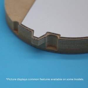 May include: Close-up of a round, light brown wooden object with a white insert. The object has a notched edge and a rectangular cutout. The background is a solid blue. Text at the bottom reads, "Picture displays common features available on some models."