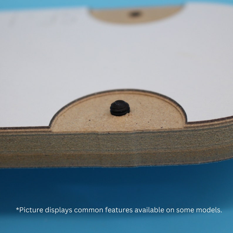 May include: Close-up of a wooden object with a white surface and a rounded, light brown edge. A black screw is centered on the light brown edge. The text at the bottom reads, "*Picture displays common features available on some models."