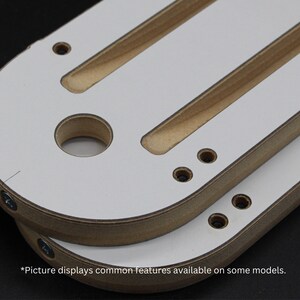 Peut inclure: Deux gabarits de toupie en bois blanc avec un bord arrondi et plusieurs trous. Les gabarits ont deux fentes longues et &eacute;troites d&eacute;coup&eacute;es dans la surface. *L'image affiche les caract&eacute;ristiques communes disponibles sur certains mod&egrave;les.*