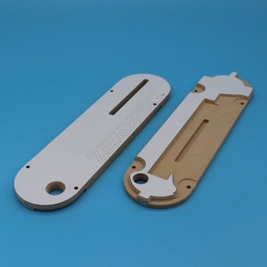 May include: Two white and brown wooden router templates with the text "ZERCSERT" printed on one of the templates.