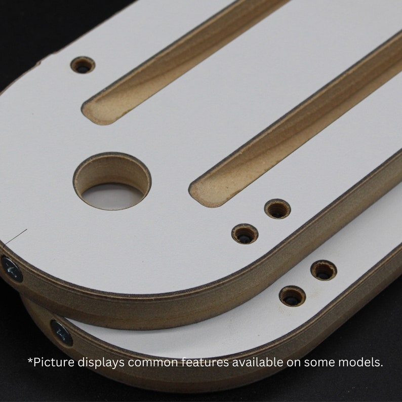 May include: Two wooden, oval-shaped pieces with a white top layer and a natural wood edge. Each piece has two parallel grooves and several drilled holes. The text "*Picture displays common features available on some models." is at the bottom.