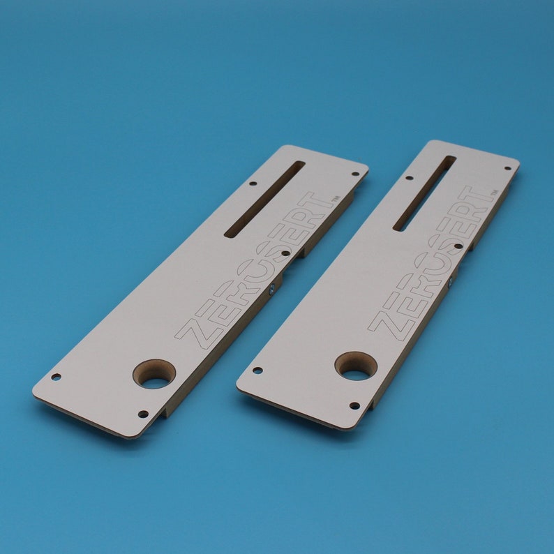 May include: Two white wooden jigs with the text "ZERUSERT" printed on them. The jigs have a slot and a hole in the centre.