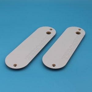 Peut inclure: Deux pi&egrave;ces rectangulaires en bois blanc aux bords arrondis et avec des trous en haut. Le texte "ZEROSERT" est imprim&eacute; sur chaque pi&egrave;ce en gris clair.