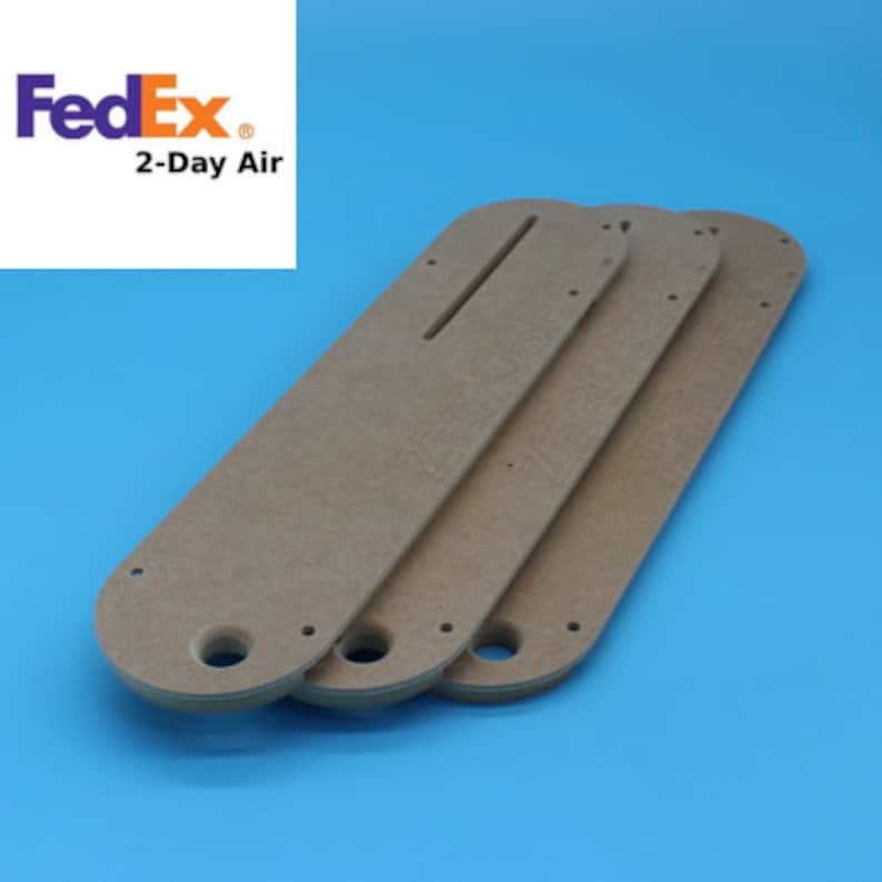 May include: Three brown wooden router templates with cutouts and holes. The templates are stacked on top of each other.