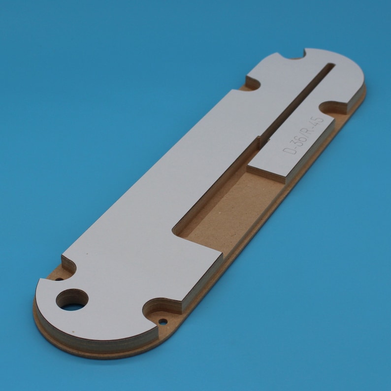 May include: A white and brown wooden template with a cutout in the shape of a letter "T" and the text "D-36R-45" printed on the side.