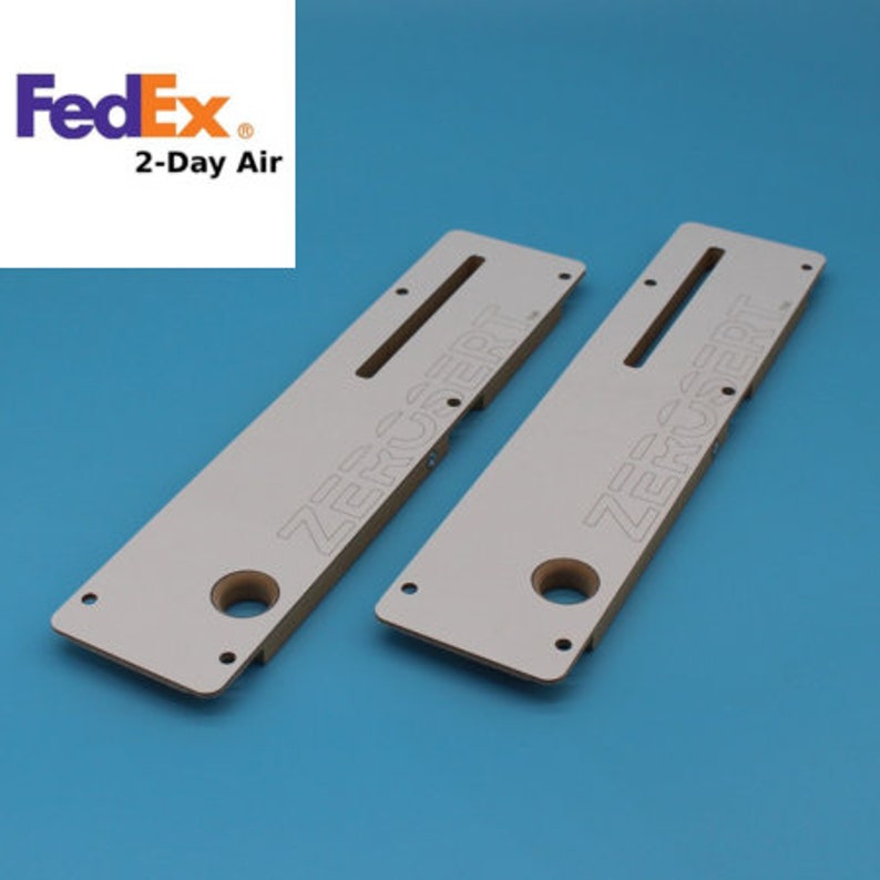 May include: Two white wooden jigs with the text "ZEROCERT" printed on them. The jigs have a slot and a hole in the centre.
