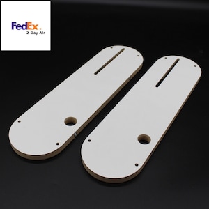May include: Two white wooden router templates with a slot and a hole in the center. The templates are designed for woodworking projects.
