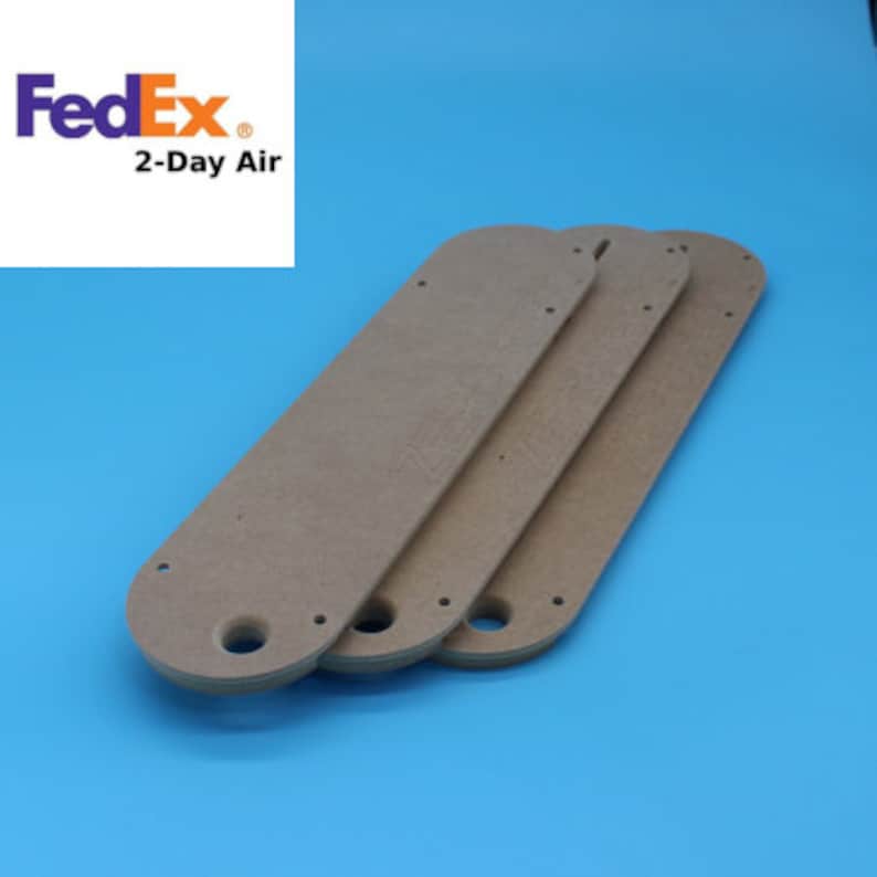 May include: Three brown wooden fan blades with holes for mounting. The blades are stacked on top of each other.