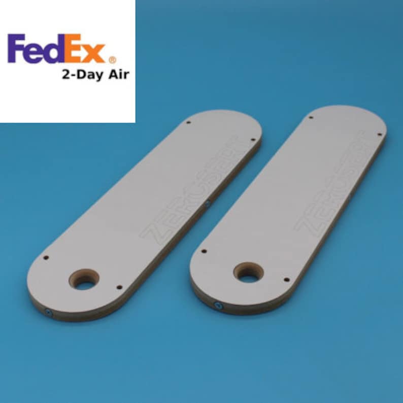 May include: Two white, rectangular router templates with the text "ZERO CLEARANCE" printed on them. The templates have a large hole in the centre and several smaller holes around the edges.