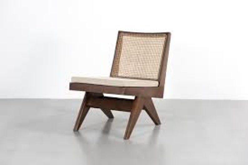 Op de afbeelding: Een stoel in mid-century modern stijl met een donkerhouten frame en een geweven rieten rugleuning. De stoel heeft een rechthoekig zitkussen en schuine poten. Afmetingen: ongeveer 71 cm hoog, 61 cm breed en 66 cm diep.