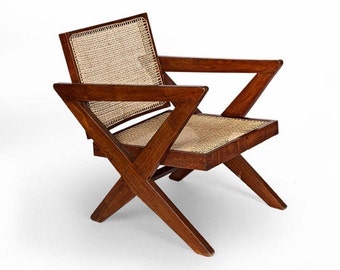 May include: A wooden armchair with a woven cane seat and back. The chair has a dark brown finish and a unique, angular design. The armrests are angled, and the legs cross for stability. The chair is a mid-century modern style.