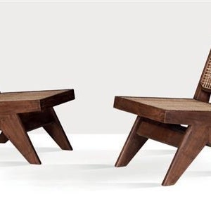 Op de afbeelding: Twee houten stoelen met een geweven rieten rugleuning en zitting. De stoelen hebben een donkerbruine afwerking en schuine poten. Perfect voor een woonkamer of zithoek, deze stoelen zijn een stijlvolle toevoeging.