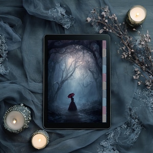May include: A black tablet displays a digital art piece of a person with a red umbrella in a dark forest. The tablet is on a blue fabric with candles and decorative elements.