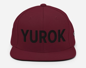 May include: A maroon baseball cap with a black embroidered logo that says "YUROK".