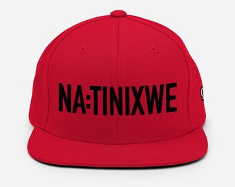 May include: A red baseball cap with a black embroidered logo that says "NA:TINIXWE".