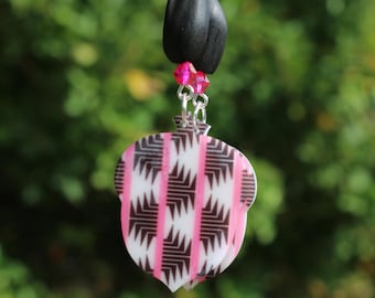May include: A pink and black patterned acorn-shaped pendant hangs from a silver chain with pink crystal beads.