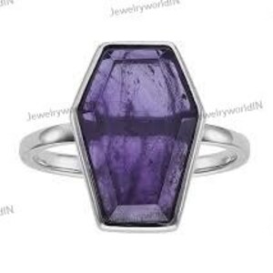 Op de afbeelding: Een zilveren ring met een grote, gefacetteerde, paarse amethiststeen in de vorm van een kist.