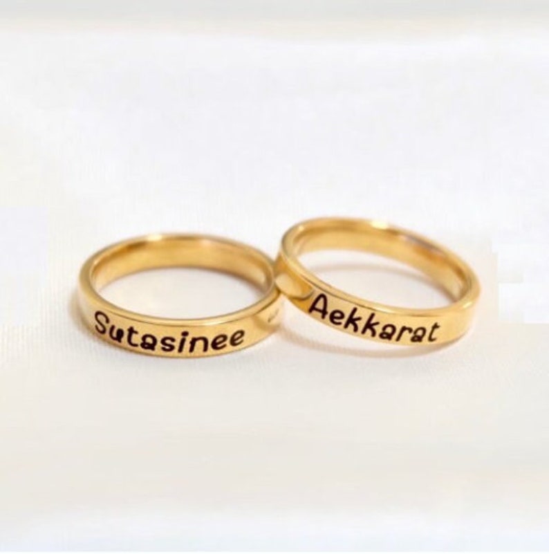 May include: Two gold-colored rings with the names "Sutasinghee" and "Aekkarat" engraved on them.