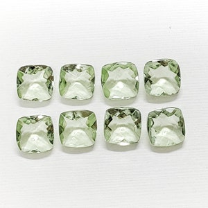 Puede incluir: Ocho piedras preciosas cuadradas de color verde claro, cada una con un corte facetado, dispuestas en dos filas de cuatro sobre un fondo blanco.