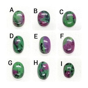 Puede incluir: Nueve piedras preciosas de forma ovalada, etiquetadas de la A a la I, con diferentes tonos de verde, rosa y negro. Las piedras están dispuestas en tres filas de tres.