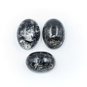May include: Three oval-shaped black and white gemstone cabochons. The stones have a translucent appearance with black inclusions.