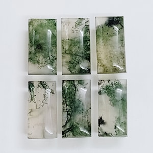 May include: Six green moss agate cabochons, each with a unique pattern of green and white. The cabochons are rectangular and have a smooth, polished surface.