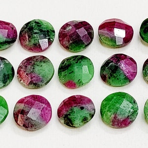 May include: Fifteen round, faceted gemstones with a mix of green and pink hues. The stones are arranged in three rows of five.