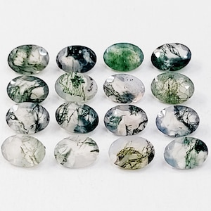 May include: A collection of 16 oval-shaped green moss agate gemstones. The stones are translucent and have a variety of green, white, and gray patterns.