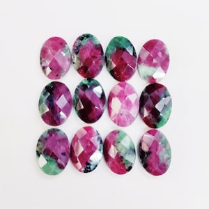 Puede incluir: Doce piedras preciosas de forma ovalada con una mezcla de colores rosa, verde y blanco. Las piedras preciosas tienen un corte facetado y están dispuestas en una cuadrícula.