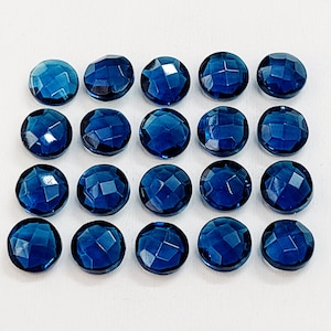 Peut inclure: Vingt cabochons de pierres précieuses bleues, chacun avec une forme arrondie facetée. Les pierres sont disposées en quatre rangées de cinq, créant un motif en grille.