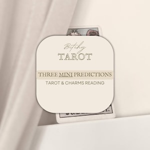 May include: A beige card with rounded corners features the text "Bitchy Tarot" and "Three Mini Predictions." The card is partially obscuring two tarot cards. The words "Tarot & Charms Reading" are also visible.
