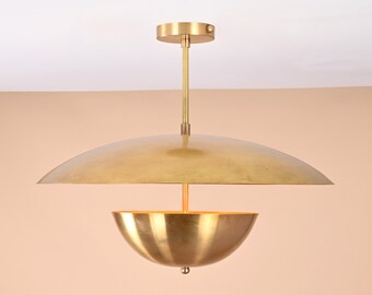 May include: A gold-toned pendant light fixture with two bowl-shaped shades. The top shade is a wide, flat disc, and the bottom shade is a smaller, rounded bowl.