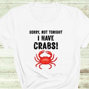 May include: White t-shirt with black text that reads "Sorry, not tonight I have CRABS!" and a red crab illustration.