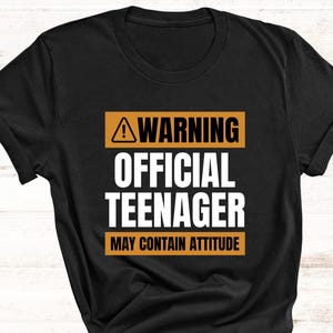 May include: Black t-shirt with a yellow warning sign and the text "WARNING OFFICIAL TEENAGER MAY CONTAIN ATTITUDE".