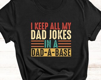May include: Black t-shirt with a vintage-style graphic that reads "I keep all my dad jokes in a dad-a-base".