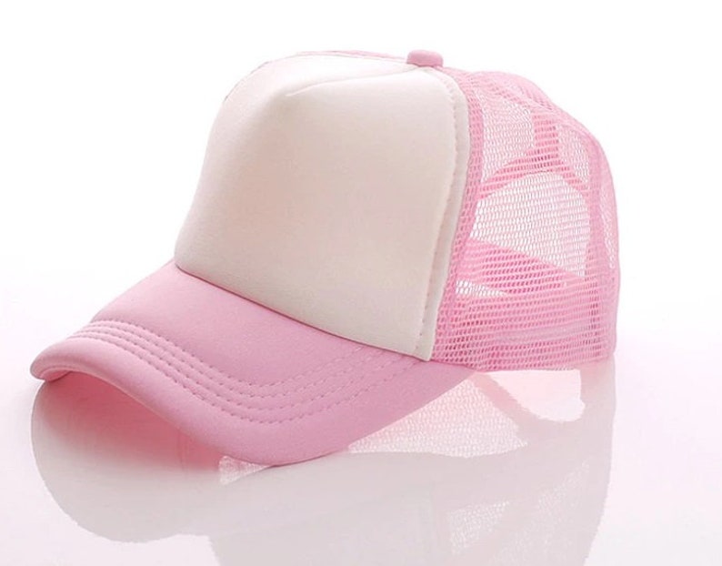 May include: A pink and white trucker hat with a mesh back. The front of the hat is solid pink and the back is a pink mesh.