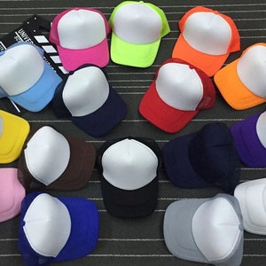 May include: A collection of 15 blank trucker hats in various colors, including red, blue, yellow, pink, orange, green, purple, brown, and black. The hats have a white front panel and a mesh back.