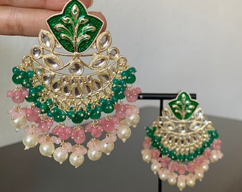 May include: A pair of gold earrings with green and pink beads. The earrings have a large, ornate design with a green leaf motif.