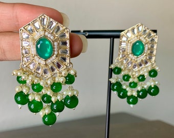 May include: A pair of gold earrings with a green gemstone center and a dangling design of green and white beads.