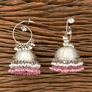 May include: A pair of silver earrings with a bell-shaped design. The earrings are decorated with white and pink beads.