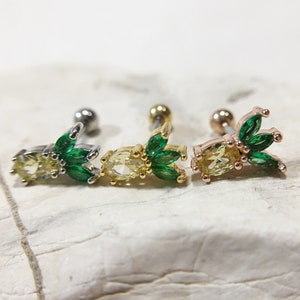 May include: Three gold, silver, and rose gold pineapple-shaped earrings with green crystal leaves. The earrings are designed for cartilage piercings.