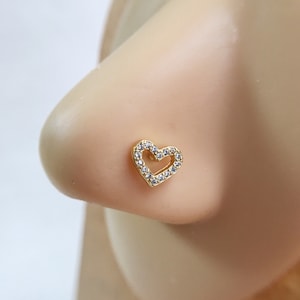 May include: A gold nose ring with a clear heart-shaped design. The heart is outlined with small clear stones.