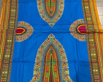 May include: A blue fabric with a colorful African print design. The fabric features a large central design with smaller designs on either side. The fabric has a gold border.