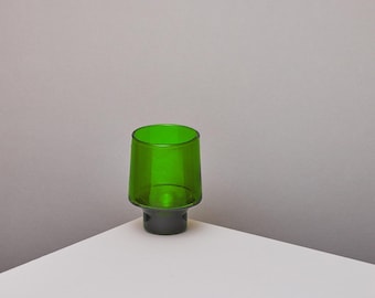 May include: A green glass tumbler with a dark green base. The tumbler is sitting on a white surface.