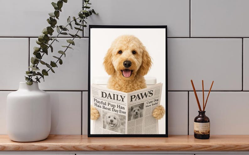 May include: A framed print featuring a golden doodle dog reading a newspaper titled "DAILY PAWS". The dog is light brown with a happy expression. The newspaper headline reads "Playful Pup Has Best Day Ever".