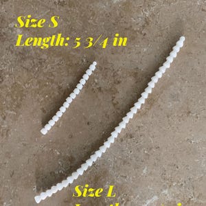 May include: Two white plastic chains, one shorter and one longer. The shorter chain is labeled "Size S Length: 5 3/4 in" and the longer chain is labeled "Size L Length: 14 1/2 in".