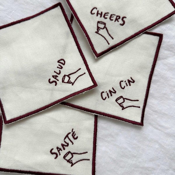 Servilletas y posavasos bordados para cócteles Cheers, Salud Sante Cin Cin, posavasos estilo Anthropologie Oliver Bonas, organización estética de cenas.