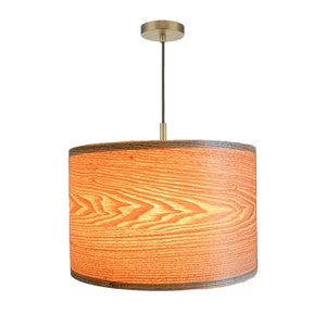 May include: A wood-grain pendant light with a brass ceiling mount and a cylindrical shade.