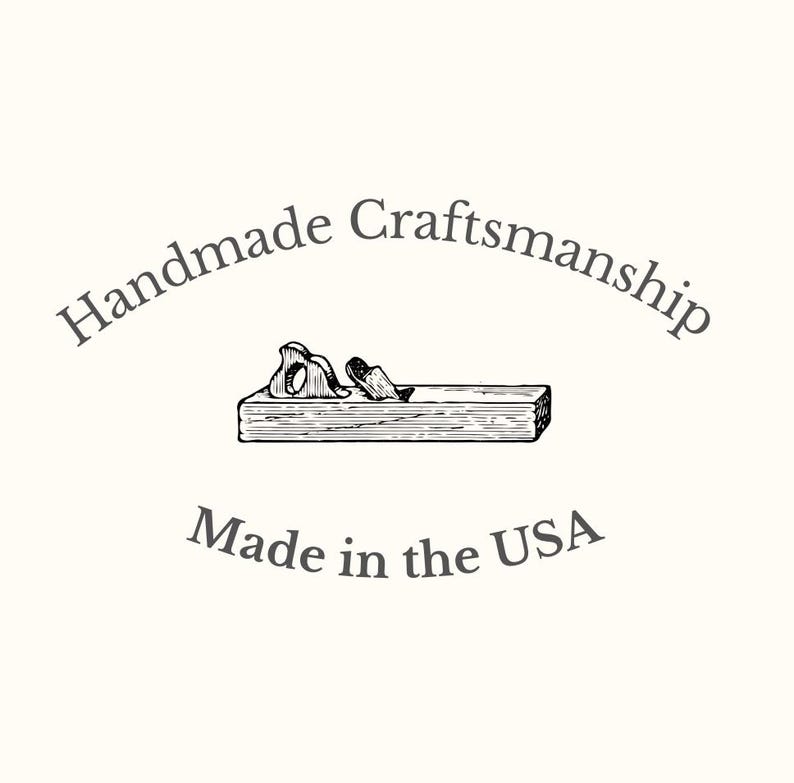 Puede incluir: Ilustraci&oacute;n en blanco y negro de un cepillo manual con virutas de madera, bajo el texto "Handmade Craftsmanship" y "Made in the USA". La imagen est&aacute; sobre un fondo crema.